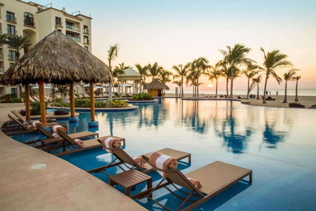 a pool at a resort with lounge chairs and palm trees at Hyatt Ziva Los Cabos - All Inclusive in San José del Cabo