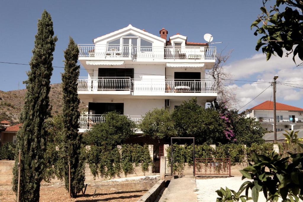 a white house with a balcony and trees at Vila Nataly in Trogir