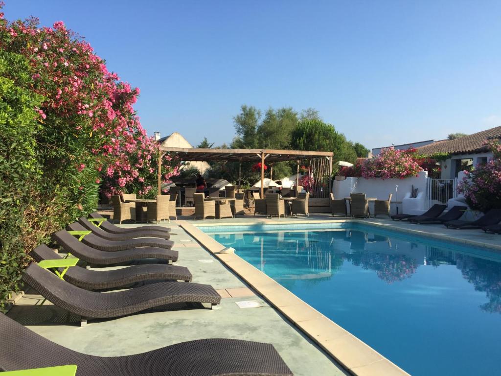 a row of lounge chairs next to a swimming pool at Mas Des Salicornes in Saintes-Maries-de-la-Mer