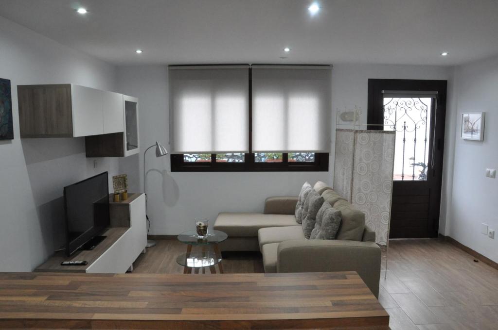 ein Wohnzimmer mit einem Sofa, einem Tisch und einem TV in der Unterkunft La Casita De Angela in Frigiliana