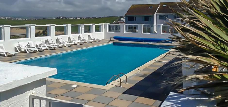 a swimming pool with chairs and a house at 34 Surfview Beach House in Newquay