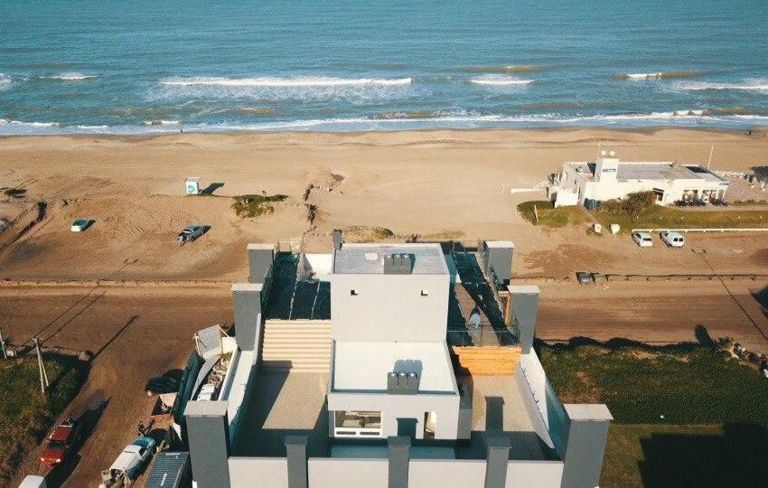 a white house on the beach with the ocean at Los Pinos Pinamar in Pinamar