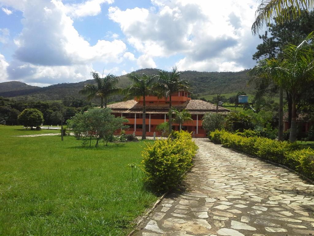 uma casa com um caminho de pedra em frente a um campo verde em Fazenda Pousada Cachoeira do Flávio em São Tomé das Letras