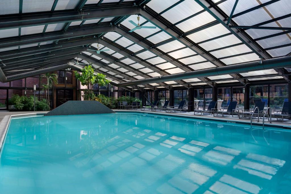 una piscina coperta con soffitto in vetro e sedie di Hyatt Regency Princeton a Princeton