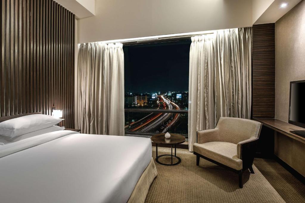 a bedroom with a bed and a window and a chair at Hyatt Raipur in Raipur