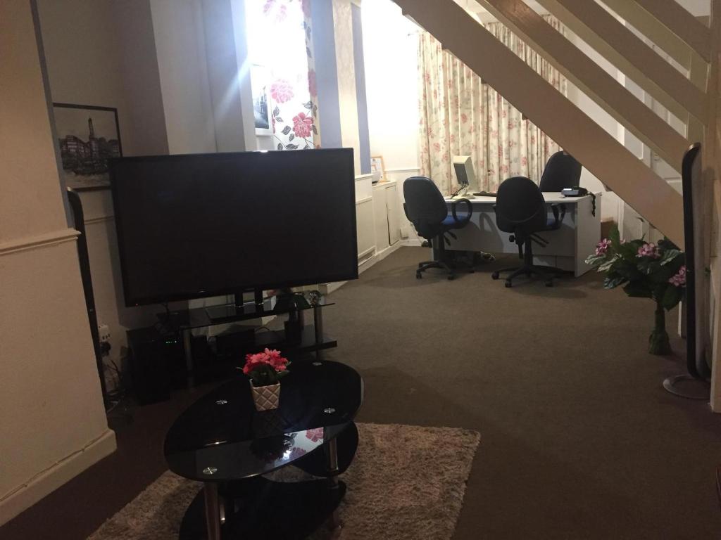 a living room with a television and a table with chairs at Double Room Home Stay Manchester in Manchester