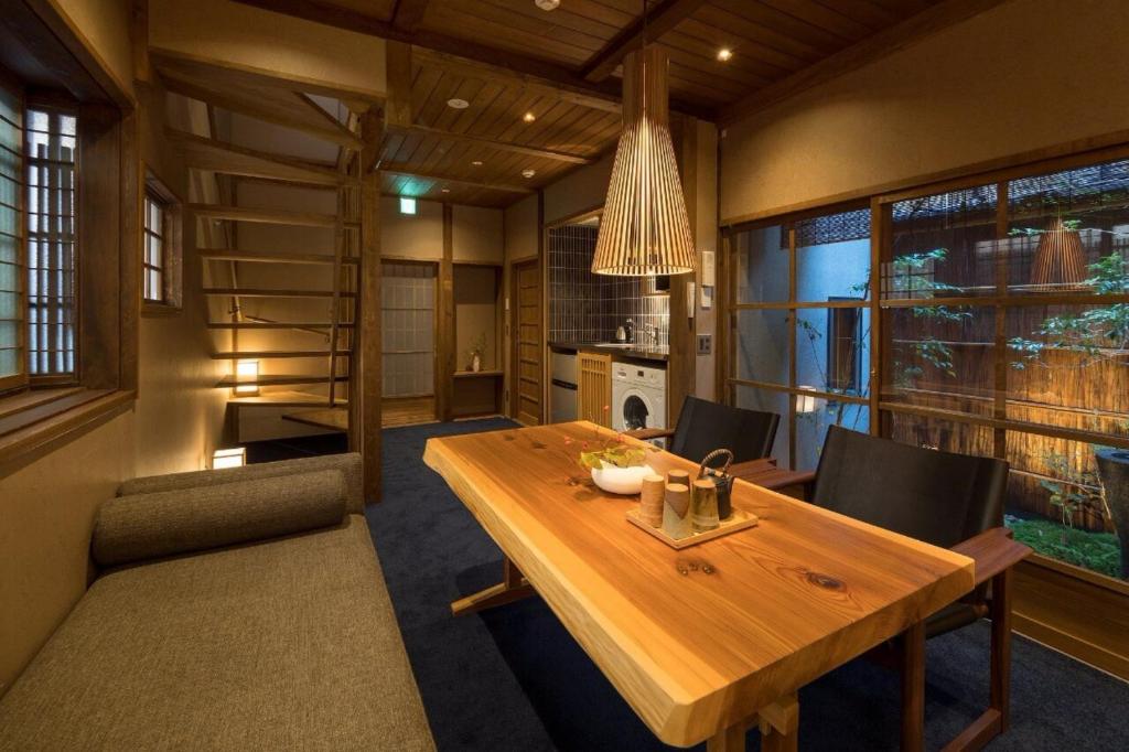 a dining room with a wooden table and chairs at Bonbori an Machiya House in Kyoto