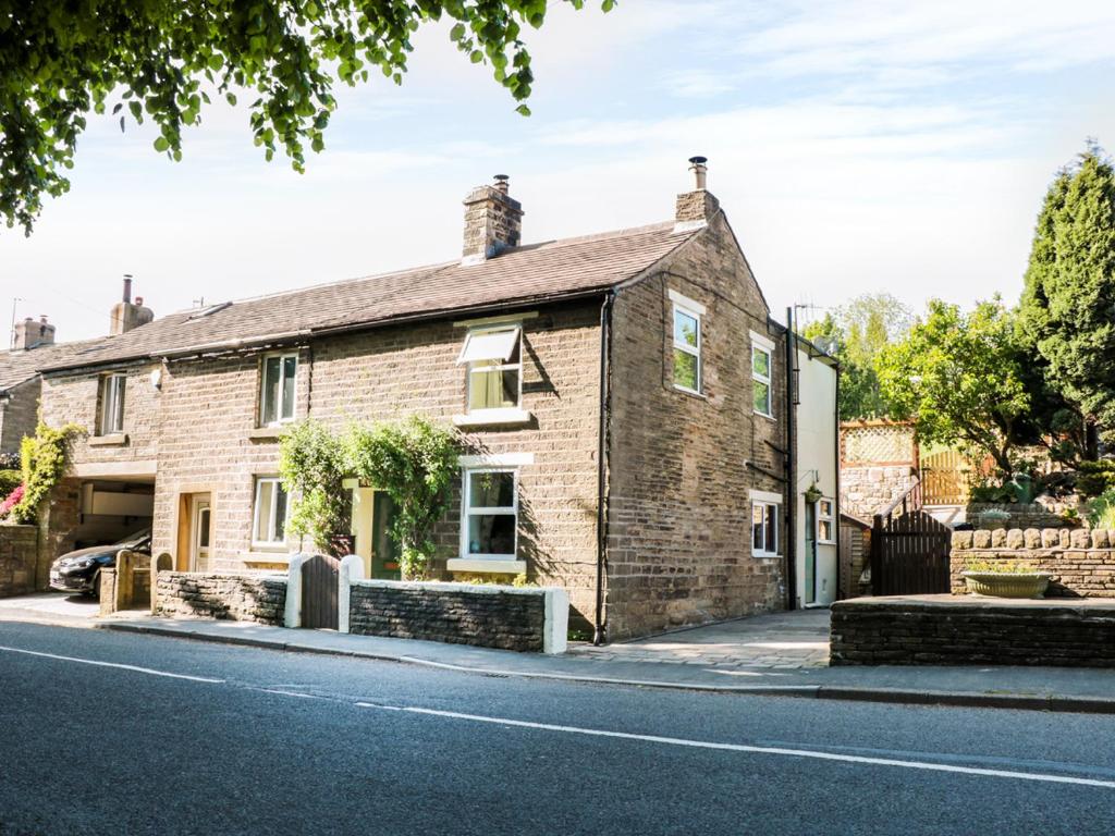 a brick house on the side of a street at Rose Cottage in Chinley