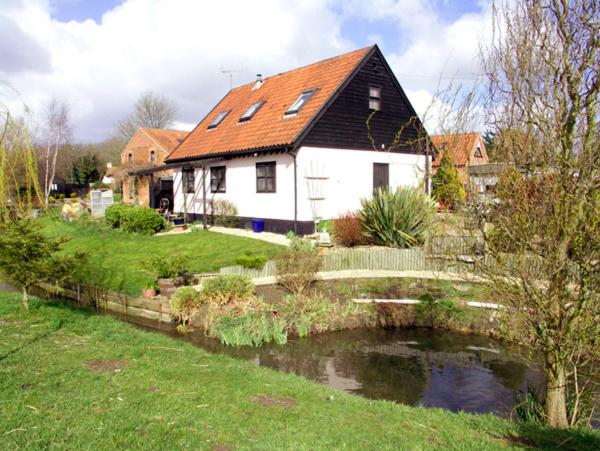 a house with a pond in front of it at The Hayloft in West Bradenham