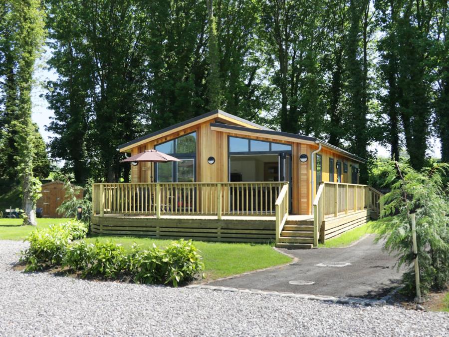 a large wooden cabin with a large deck at Squirrel Lodge in Skipton