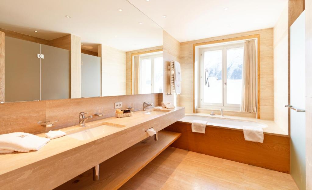 uma casa de banho com 2 lavatórios e um espelho grande em Art Boutique Hotel Monopol em St. Moritz