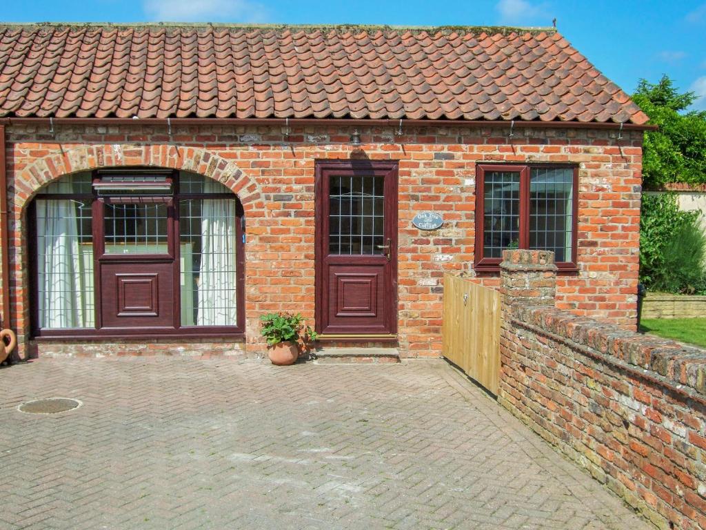 a brick building with a wooden door and a fence at Oak Tree Cottage in Beverley