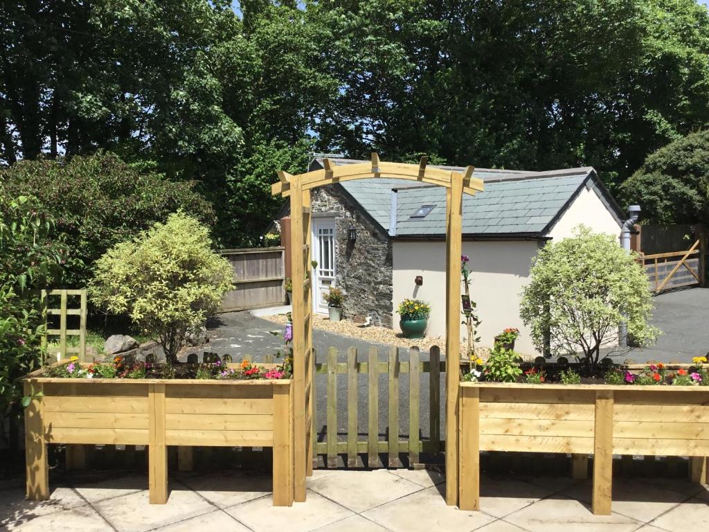 uma cerca de madeira com um portão e algumas flores em Bramble Barn em Bodmin