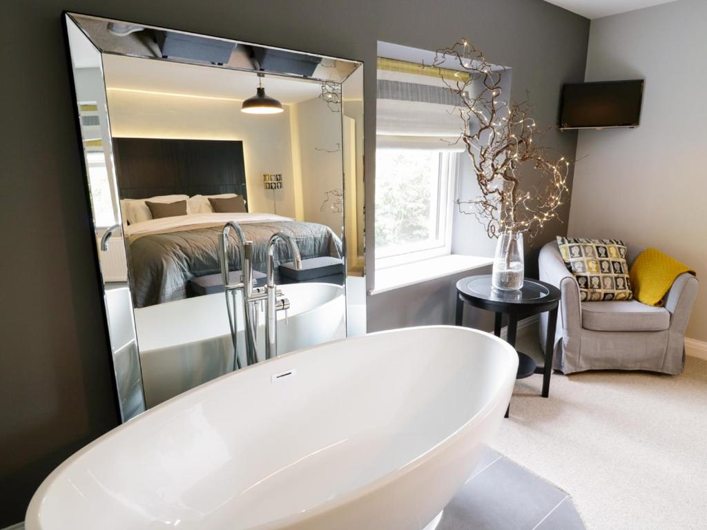 a bathroom with a white tub and a bedroom at The Old Post Office in Garstang