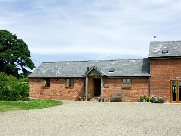 ein Backsteinhaus mit einer Einfahrt davor in der Unterkunft The Byre in Bishops Castle