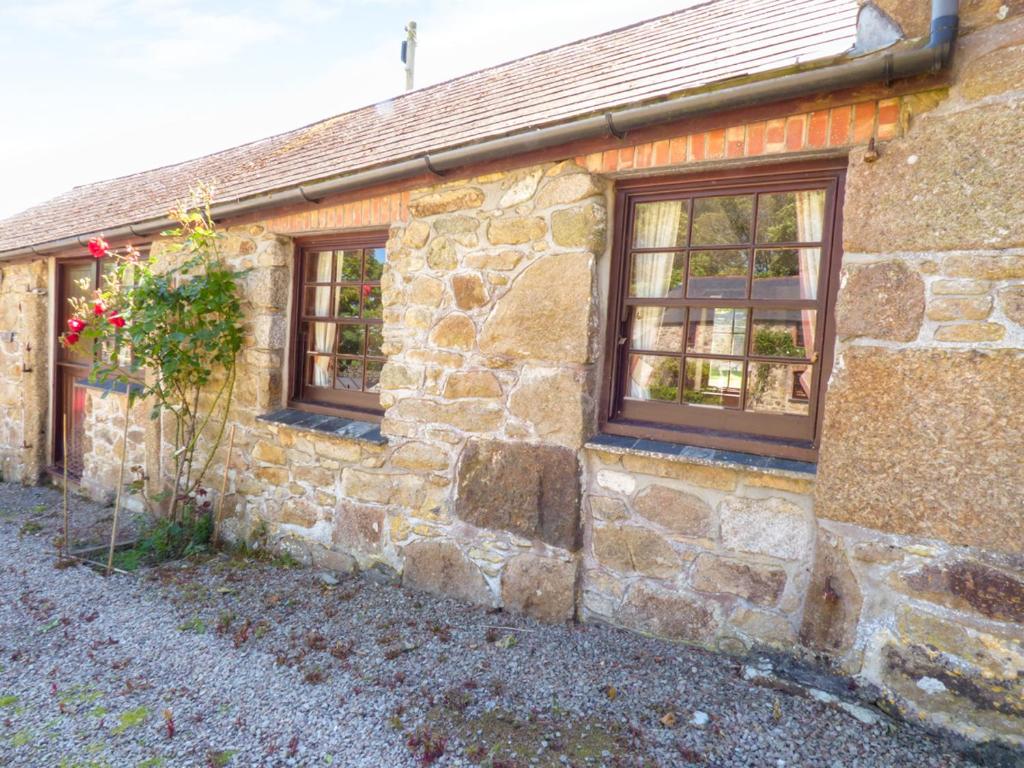 una casa de piedra con tres ventanas en un lateral. en Parlour Cottage en Saint Erth