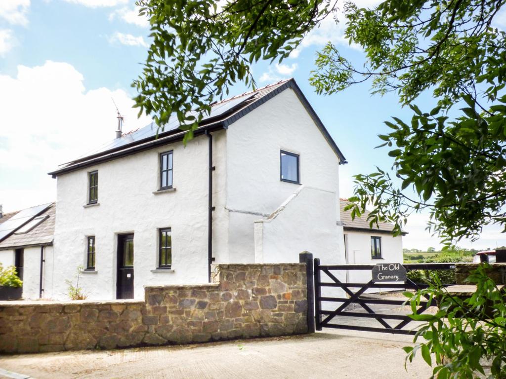 una casa blanca con una puerta y una valla en The Old Granary, en Haverfordwest