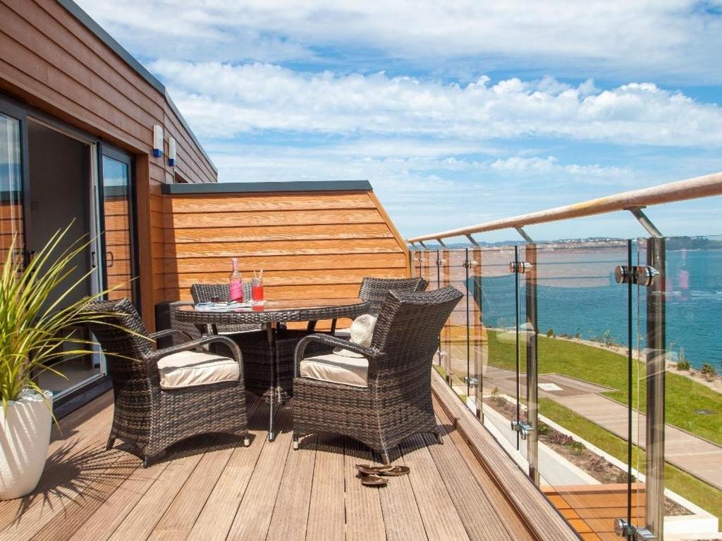 a patio with a table and chairs on a balcony at Bayview in Brixham