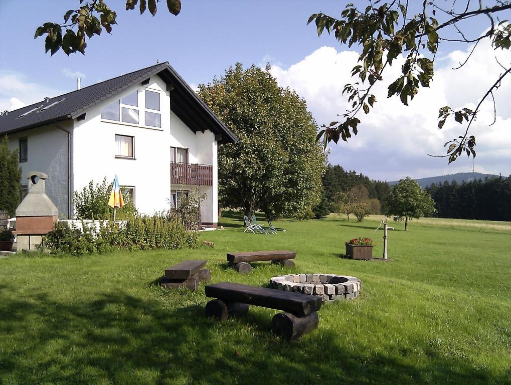 ビショフスグリュンにあるFerienhof Höhenluftの芝居の火台とベンチのある白い家