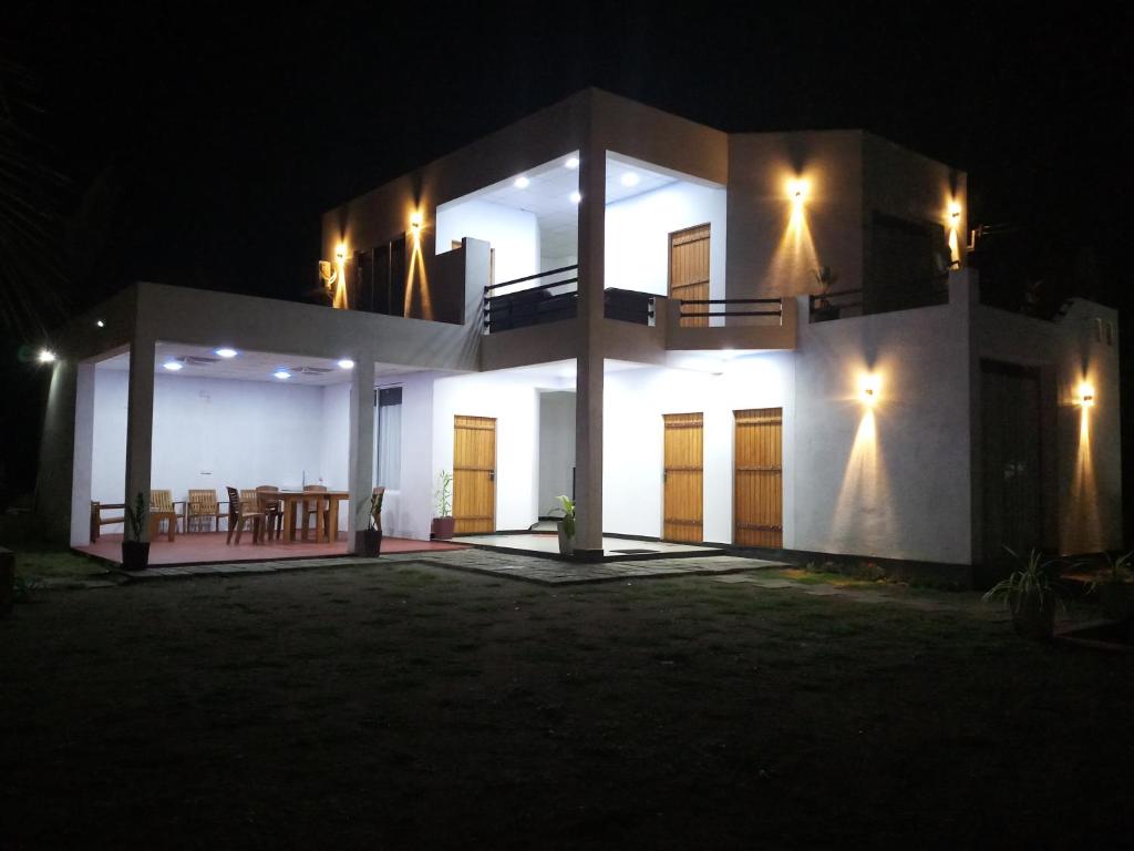 Cassia Udawalawe في اوداوالاوي: منزل أبيض كبير في الليل مع أضواء