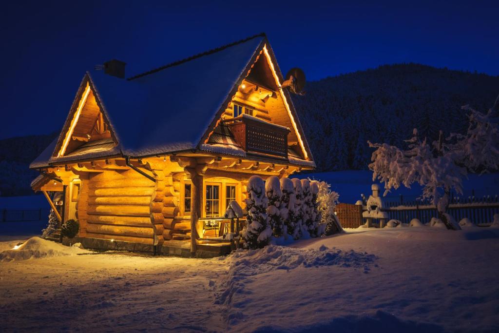 a log cabin in the snow at night at Domek Otulina in Zakopane