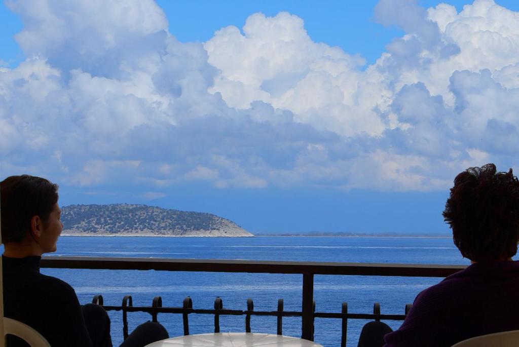 dos personas sentadas en una mesa mirando hacia el océano en Akti Hotel, en Limenas