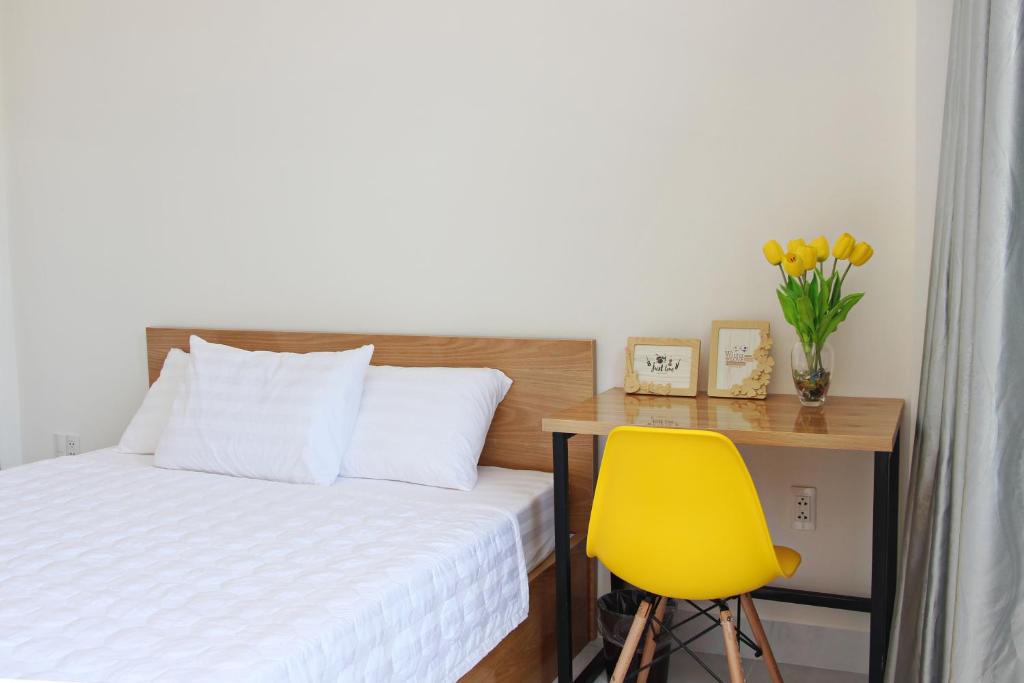 a bedroom with a bed and a desk with a yellow chair at 91 Homestay, Cafe, Bonsai in Vung Tau