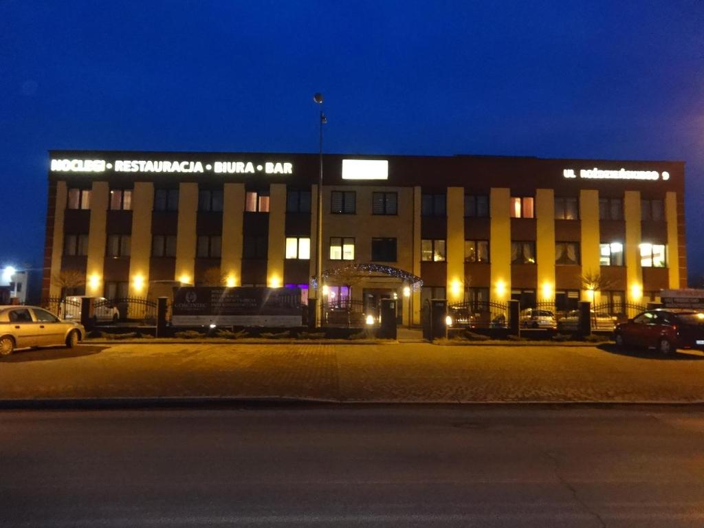 un gran edificio por la noche con coches estacionados en un estacionamiento en Gościniec Biznesowy en Dąbrowa Górnicza