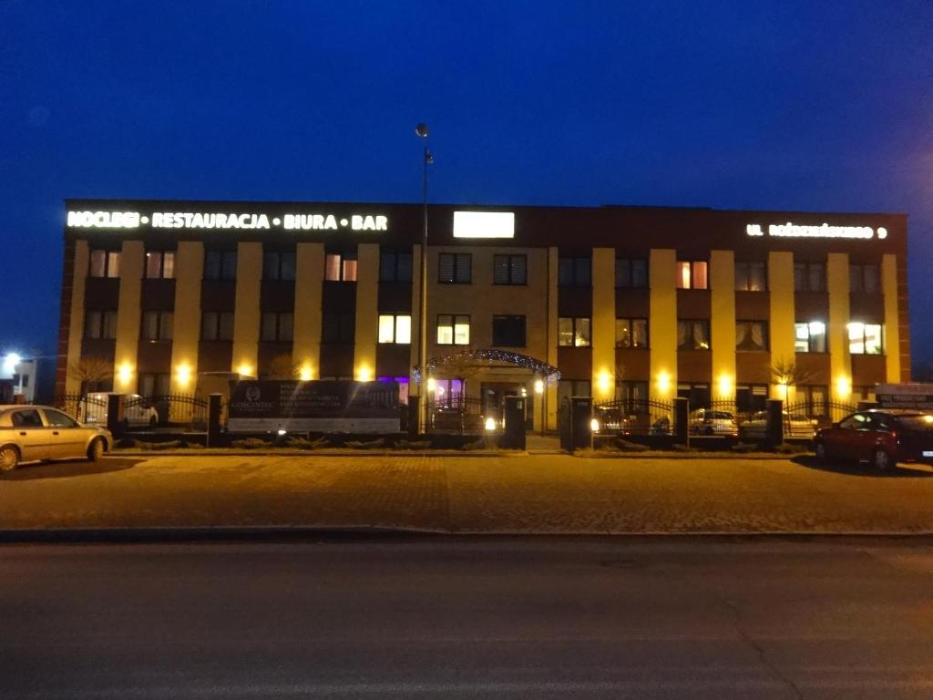 un gran edificio por la noche con coches estacionados en un estacionamiento en Gościniec Biznesowy, en Dąbrowa Górnicza