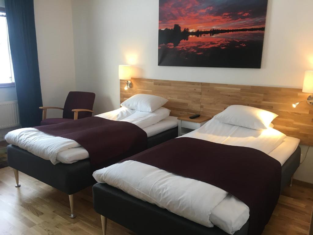 a hotel room with two beds and a painting on the wall at Munken Hotell & Konferens in Mönsterås