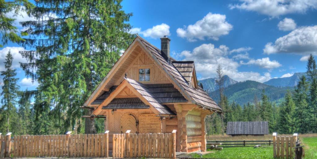 a log cabin with a wooden fence at Domki Odpocywadło in Witów