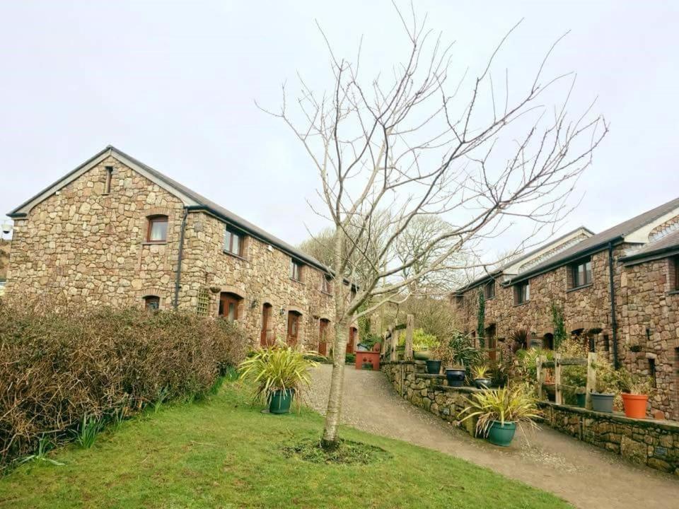 a brick building with a tree in front of it at King's Head Inn in Llangennith