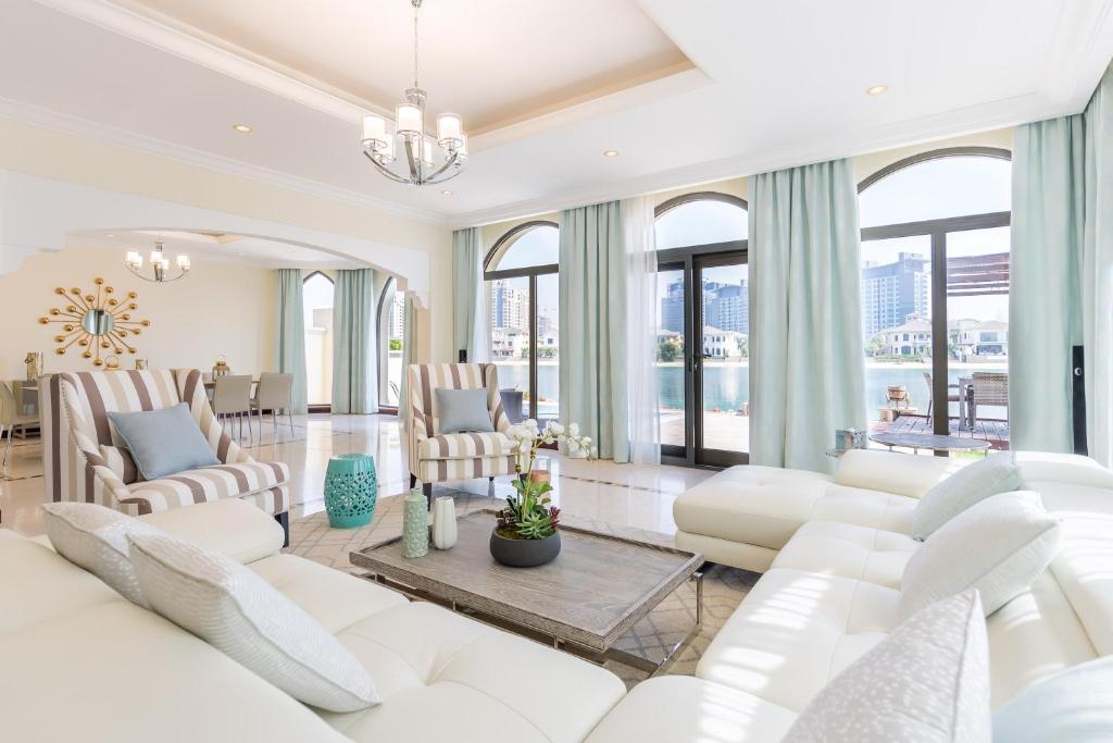 a living room with white furniture and large windows at Charming 6BR Villa with Private Pool on Palm Jumeirah in Dubai