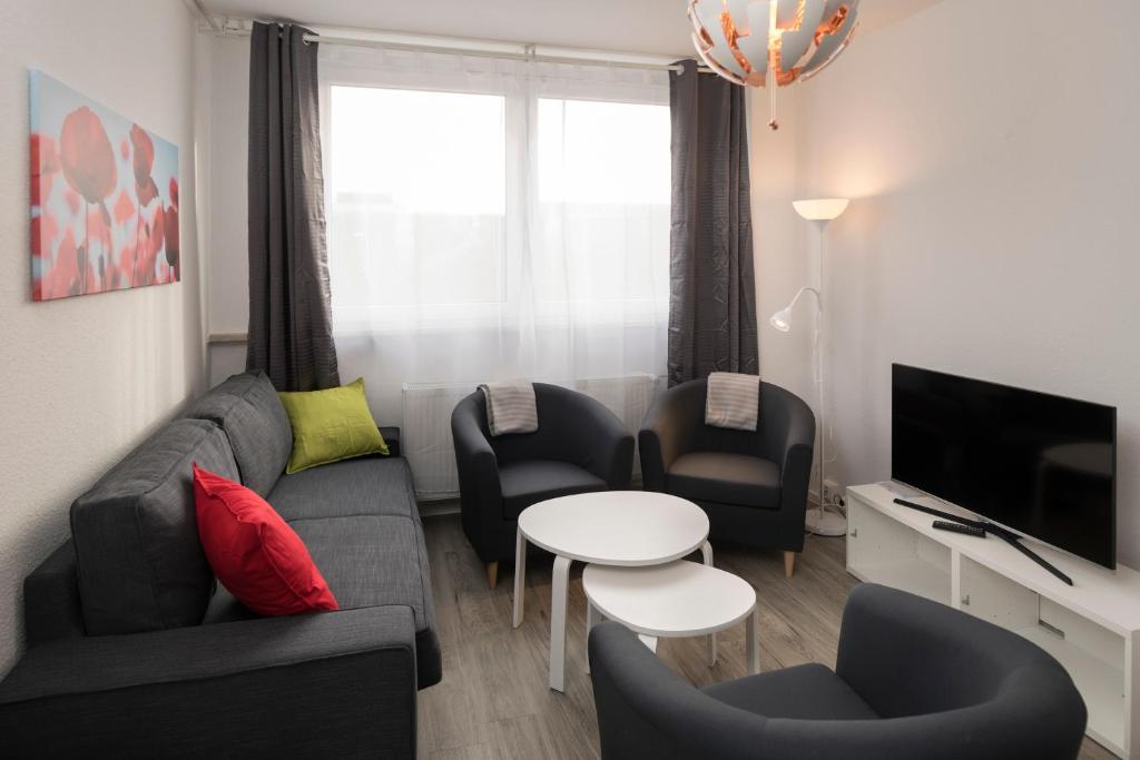 ein Wohnzimmer mit einem Sofa, Stühlen und einem Tisch in der Unterkunft GWG City Apartments III in Halle-Neustadt