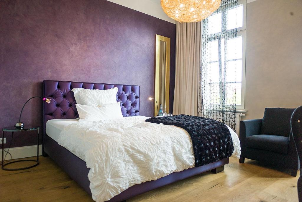 Fioletowa sypialnia z łóżkiem i krzesłem w obiekcie Designhotel Rosenbohm w mieście Oldenburg
