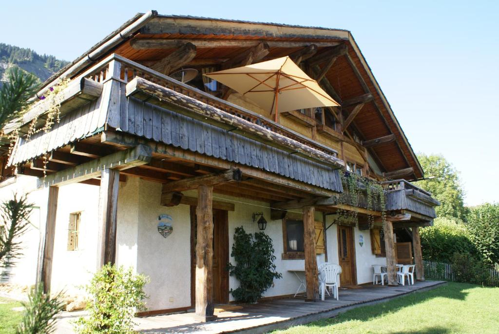 une maison en bois avec un parasol et des chaises dans l'établissement Chalet du Renard, à Flumet