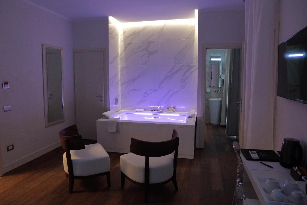 un bagno con un grande lavandino bianco e sedie di Palazzo Cini Luxury Rooms in Pisa a Pisa