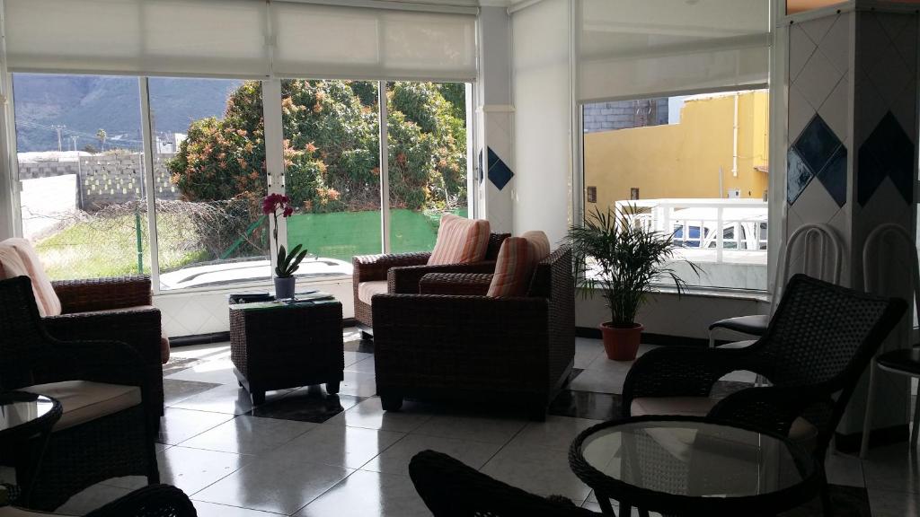 una sala de espera con sillas, mesa y ventanas en Hotel Los Cascajos, en San Nicolás