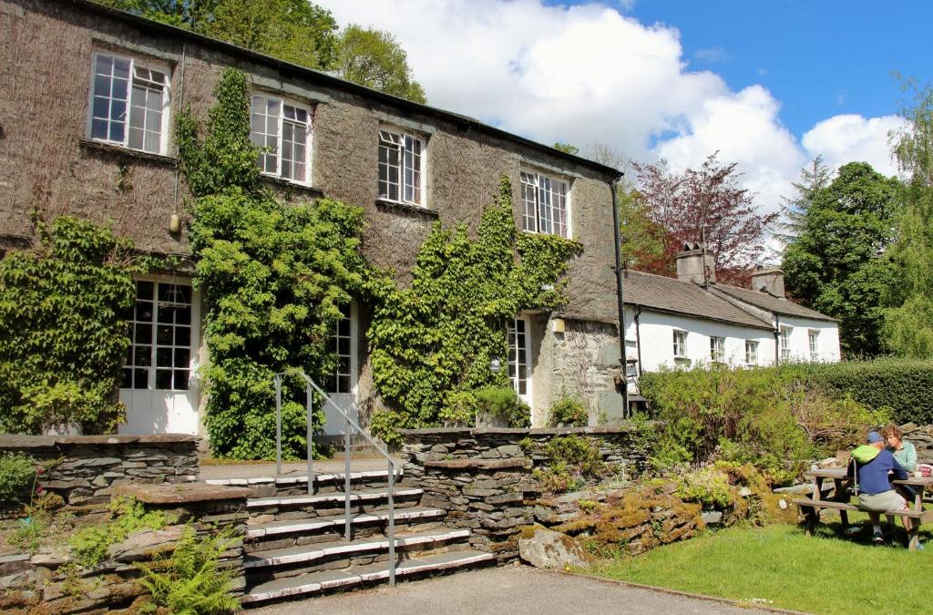 um homem sentado num banco em frente a um edifício em Elterwater Hostel em Elterwater