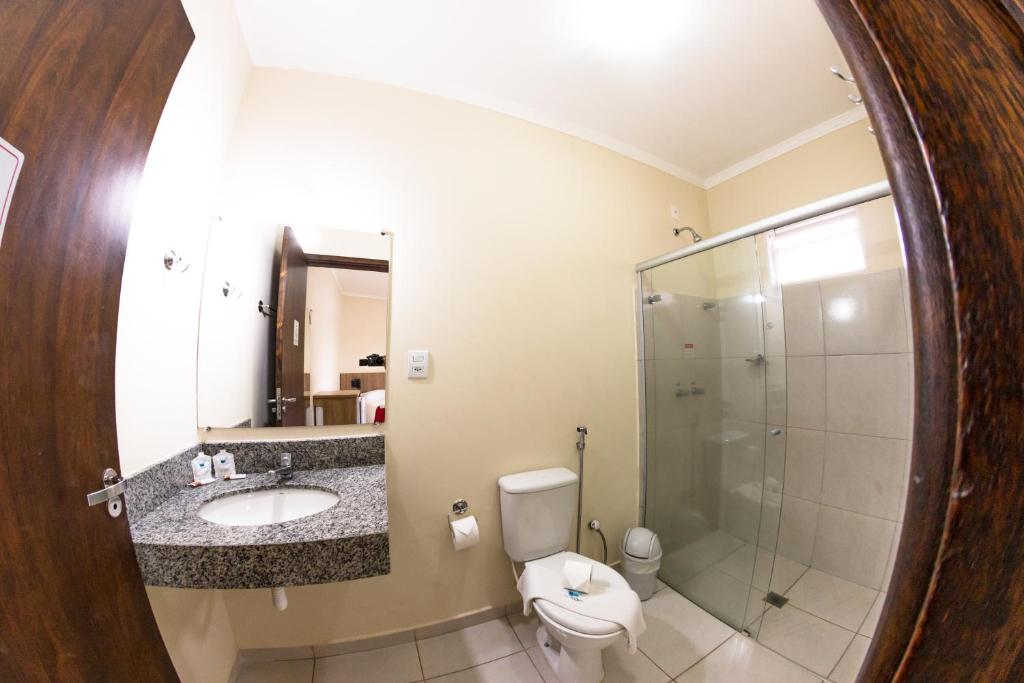 a bathroom with a toilet sink and a shower at Pousada Toca das Águas in Olímpia