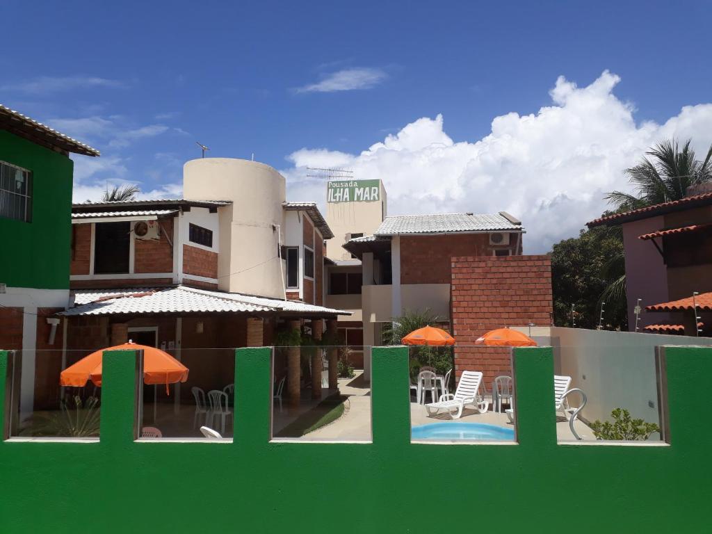 a green fence in front of a building with a pool at Pousada Ilha Mar in Barra de Santo Antônio
