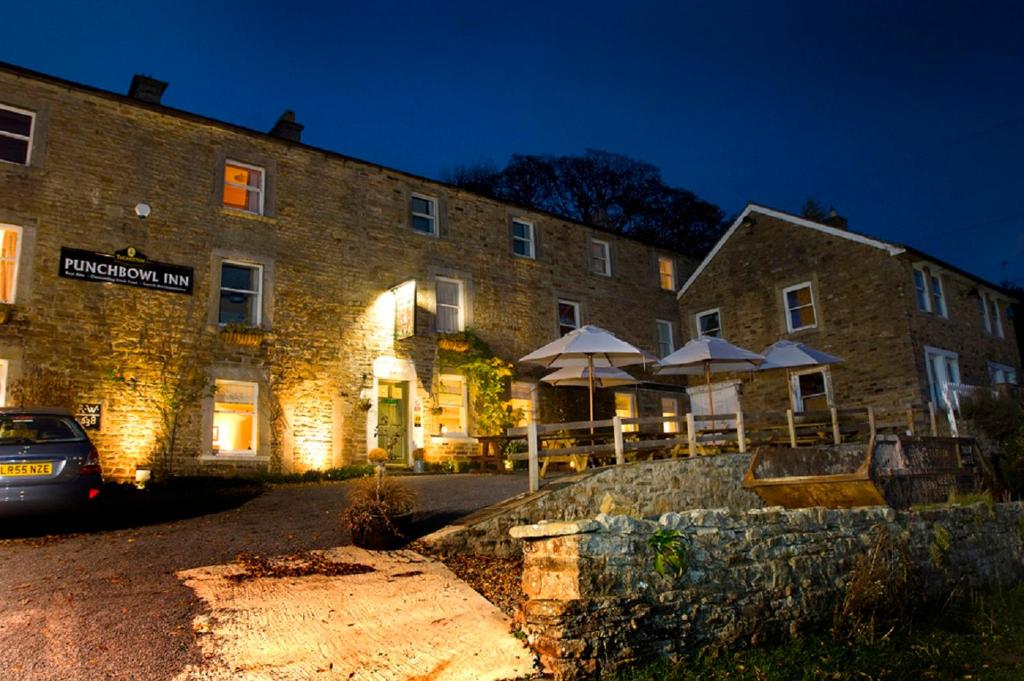 a large brick building with umbrellas in front of it at The Punch Bowl Inn in Feetham