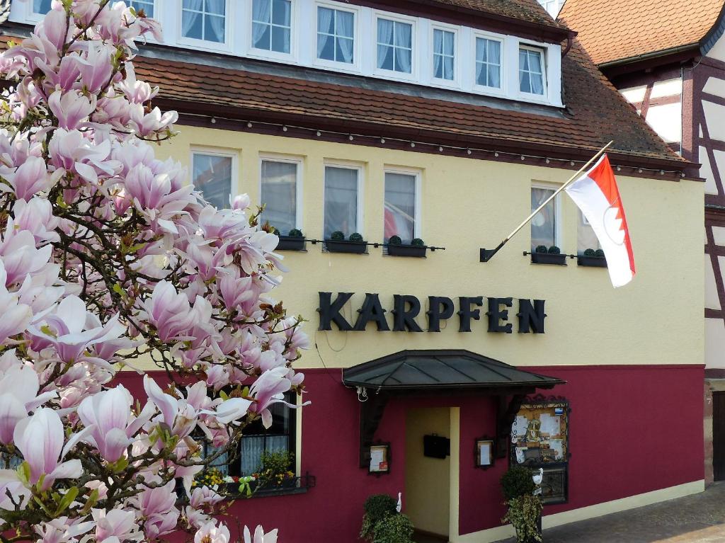 美茵河畔奧伯恩堡的住宿－Hotel & Restaurant Zum Karpfen，一座卡里尔建筑,前面有一棵开花的树