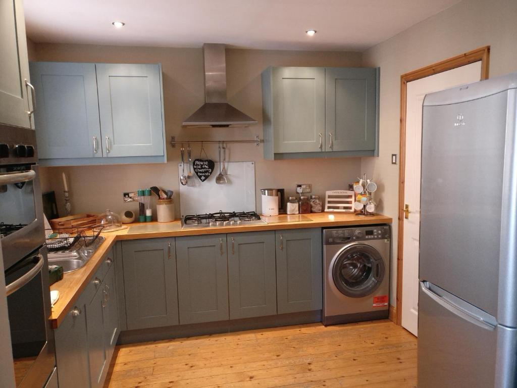 a kitchen with blue cabinets and a washer and dryer at Colegate 4 Bed townhouse in Norwich