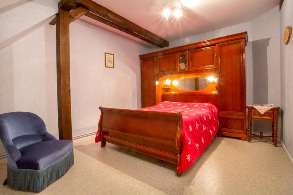 a bedroom with a bed and a chair at Chez Christian in Breitenbach-Haut-Rhin