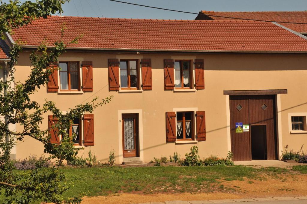 ein altes Haus mit Holzfenstern und -türen in der Unterkunft la grange aux hirondelles in Athienville