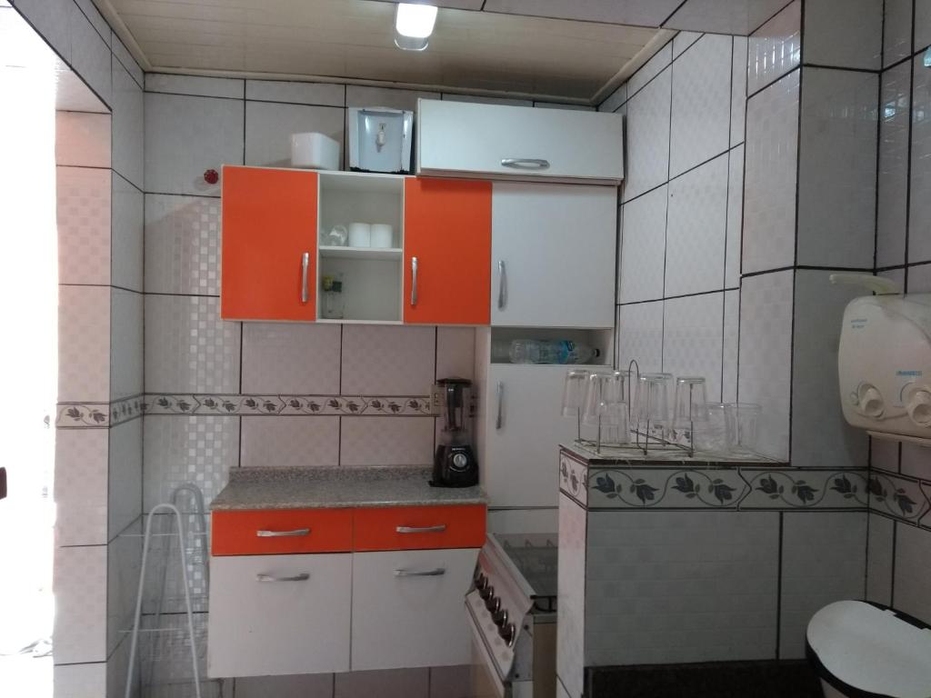eine Küche mit orangefarbenen und weißen Schränken und einem Waschbecken in der Unterkunft Casa de Cabo Frio 28 in Cabo Frio