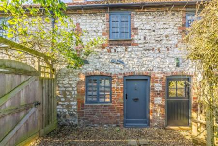 a brick house with a blue door and a fence at No33 THORNHAM BOUTIQUE COTTAGE 2 in Thornham