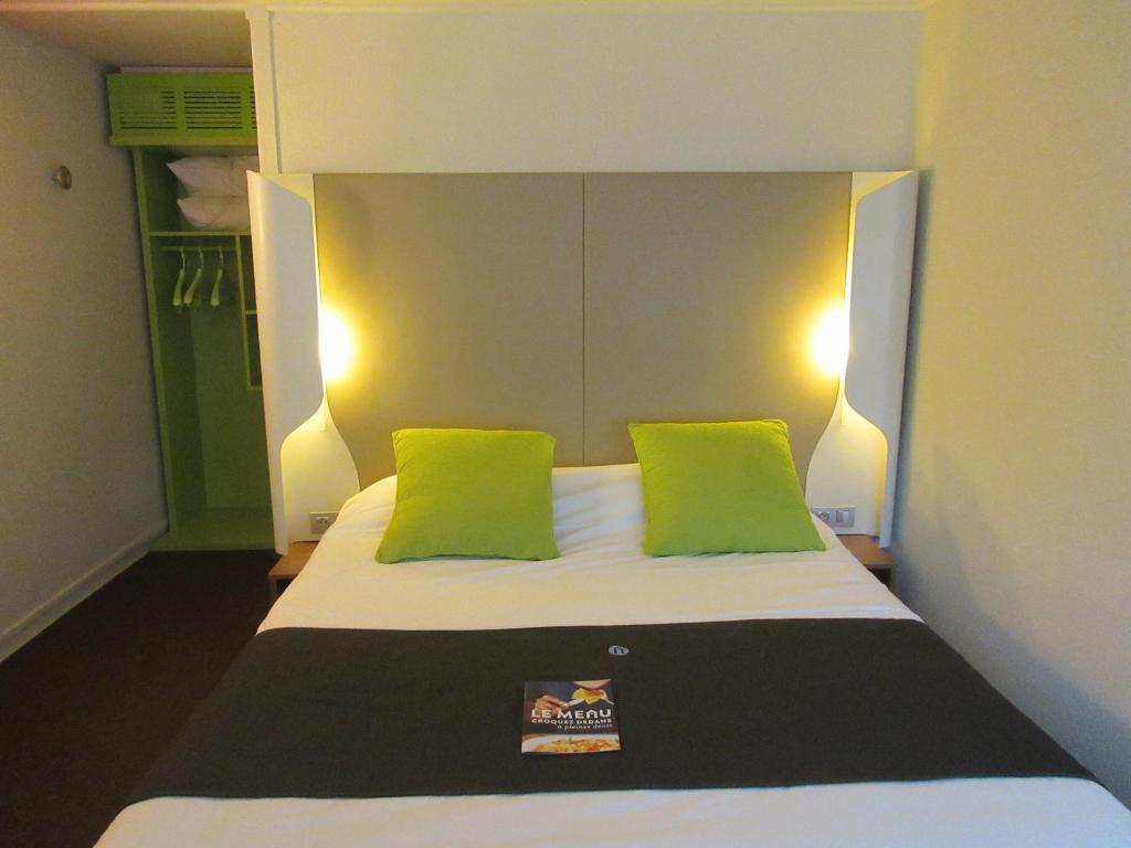 a bedroom with a bed with green pillows at Campanile Bayeux in Bayeux