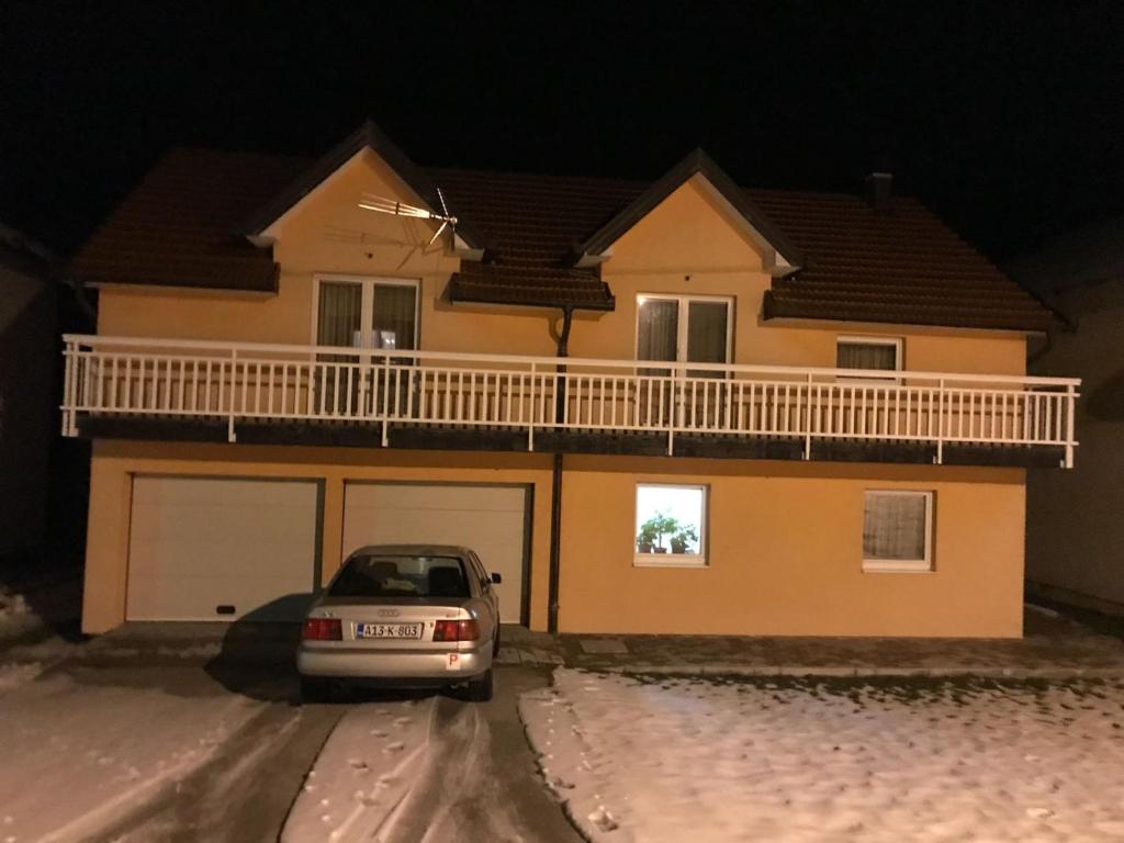 un coche aparcado frente a una casa en la nieve en Jelena, en Kupres
